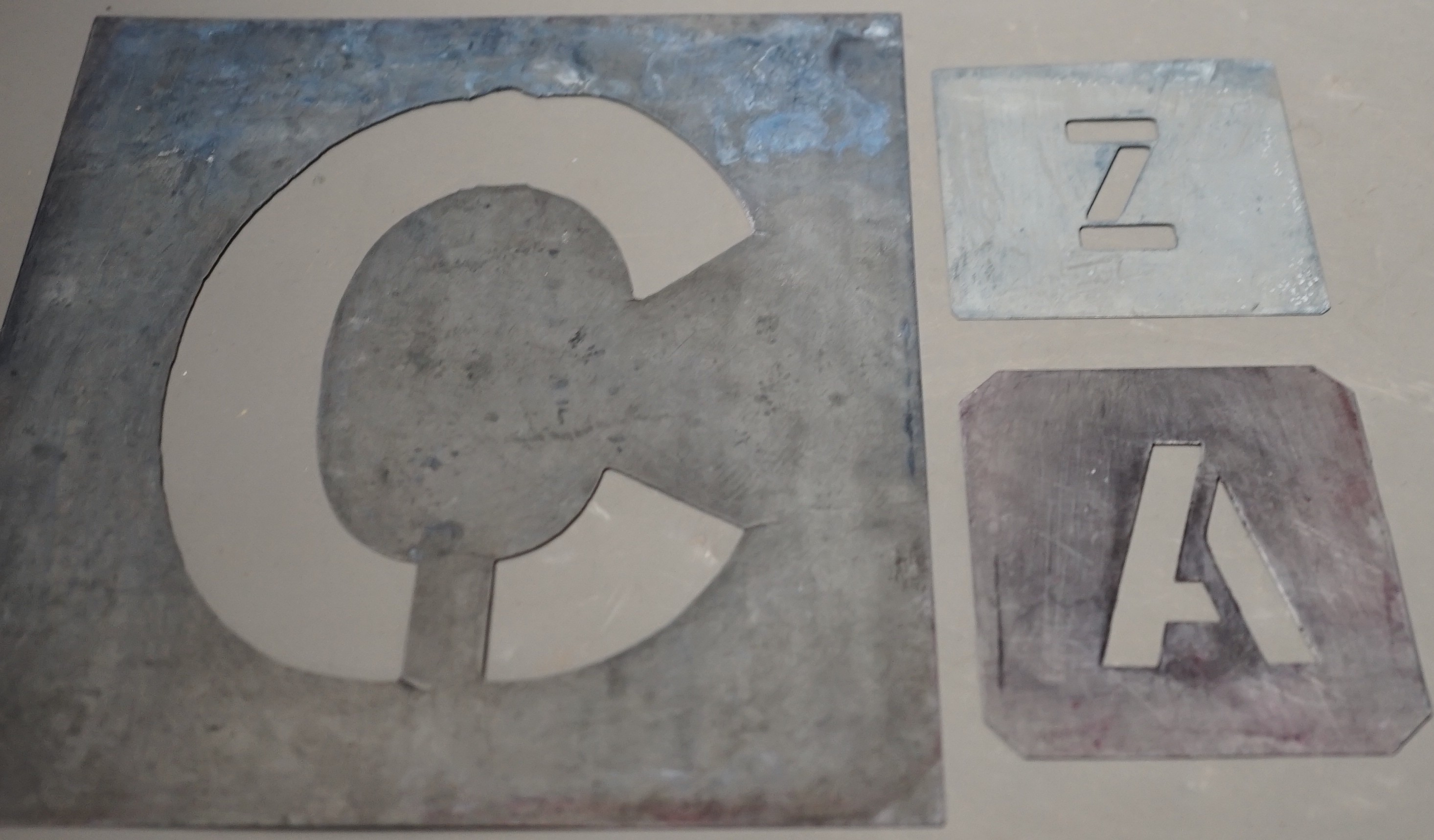 A complete set of zinc alphabet stencils, two incomplete sets of alphabetic stencils and one complete set of numerals